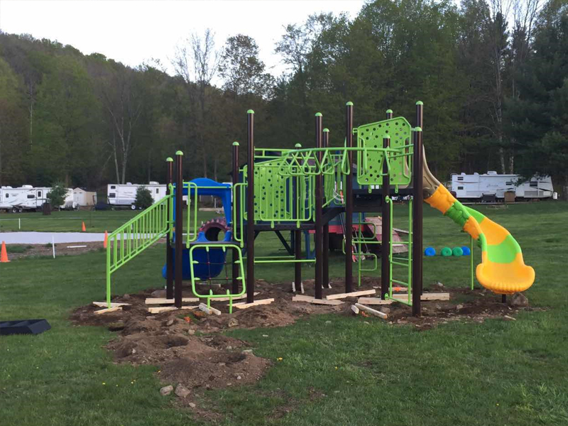 This campground outdoor playground brings outdoor excitement and physical challenge to children of all abilities. Set in a grassy area surrounded by nature, it features a sturdy climbing structure with monkey bars, rope elements, and a twisty tunnel slide. Kids can grip, climb, balance, and slide—using touch and movement to explore the space. Designed for safety and fun, this playground encourages active play, social connection, and a true sense of adventure in the heart of the campground.