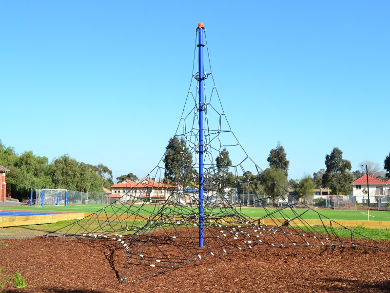 This project features a pyramid rope climber—a tall, cone-shaped play structure made of interwoven ropes that rise from the ground to a central peak. Located in an open schoolyard surrounded by trees and grassy fields, the structure invites children to climb, balance, and explore at their own pace. The ropes form a wide base that gradually narrows as it reaches the top, resembling a climbing mountain made of tensioned cords. It’s designed to promote strength, coordination, and imagination, offering an exciting yet safe challenge for school-age kids.