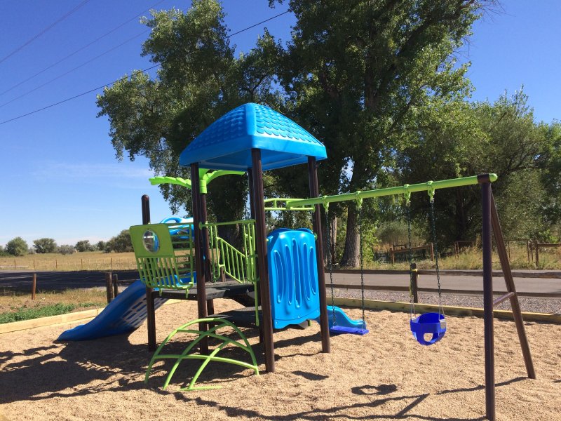 This small KidsVenture backyard outdoor playset is thoughtfully designed for residential use. It features an arch climber that leads up to the deck, where two bright blue slides offer exciting fun for young children. A swing is also attached to the structure, giving kids the thrill of movement and moments of pure exhilaration—all in the comfort of their own backyard.
