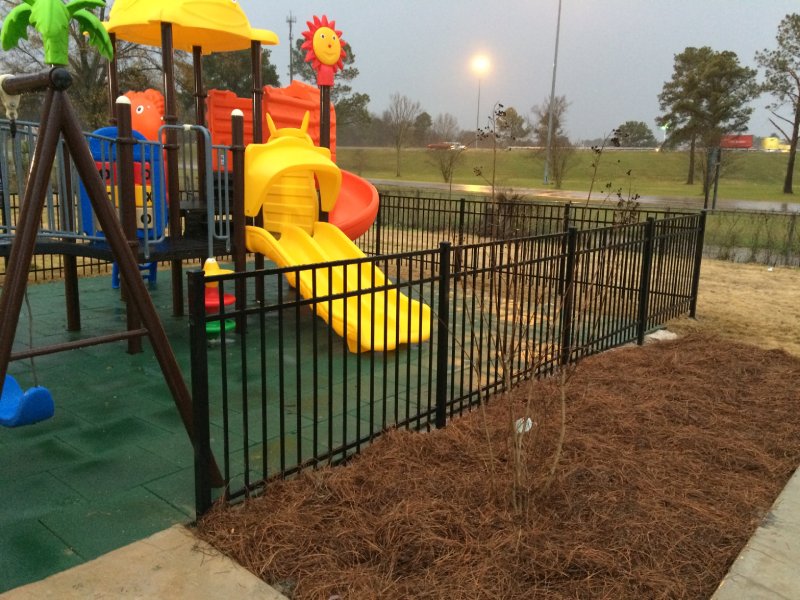 This vibrant playset was designed for a shopping centre playground in the Midwest United States. Featuring a nature-inspired tree theme, it includes a single orange curved slide, a yellow double straight slide, a blue arch climber, and several orange play panels. A cognitive number board adds an educational element for younger children. The structure is topped with green tree-themed accents, along with one yellow and one blue roof. Suitable for children ages 2 to 12, this photo highlights the yellow double slide.