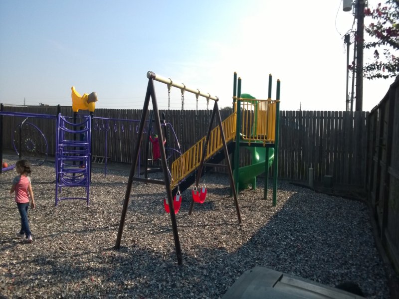 This custom-designed project was created for an elementary school outdoor playground. It features a variety of play elements suitable for children ages 2 to 12. A 5-foot-high standalone play structure with a bright yellow railing and a vibrant green spiral slide adds excitement for older kids. A classic monkey bar invites children ages 4 and up to test their courage and upper-body strength. Multiple net climbers challenge children of all ages to develop balance and coordination. The lower deck, equipped with two small purple parallel slides, creates a welcoming space for younger children to play together and build social skills. The inclusive design also ensures children with disabilities can enjoy outdoor play in a safe and engaging environment. Nearby, a swing offers younger children the thrill of motion while helping them bond with caregivers. This photo highlights the arch climber.