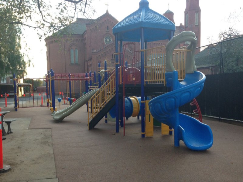 This custom-designed playground was created for an elementary school in Sydney, Australia, with a perfect balance of fun for all age groups. It features a variety of upper body challenges like monkey bars, a climbing wall, and several net climbers. We also included one of our signature KidsVenture play structures. Bright blue posts paired with bold red frames and rings give the space a vibrant, energetic feel. The main play structure extends the blue theme with a matching roof, yellow railings, and two slides — one open and one fully enclosed. The playground is built to engage kids from ages 2 to 12. Younger children can enjoy climbing and crawling on the play structure, while older kids can test their strength and coordination on the monkey bars and climbing wall. This photo highlights the blue play structure.