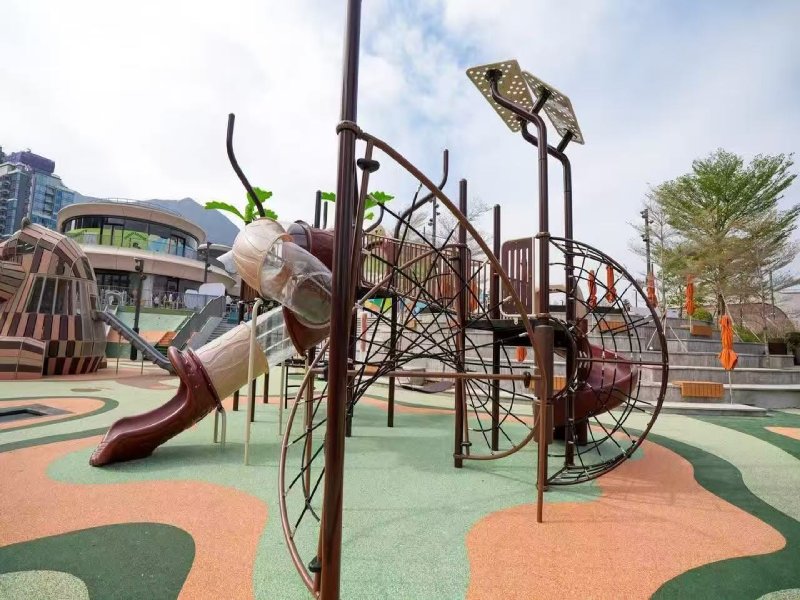 KidsVenture’s wave barrel style net climbing structure — a bold architectural piece that immediately draws attention with its sculptural curves and open-air barrel form. This unique design allows children to climb, crawl, and balance within a safe yet thrilling environment. The layered climbing levels, made from durable tensioned rope netting, challenge children of various ages while promoting coordination, strength, and confidence. Adding to the excitement is a fully enclosed spiral slide with transparent sections, seamlessly integrated into the structure’s frame. The slide not only adds an adrenaline-filled descent but also offers visual delight through the clear panels, letting light pour in and allowing parents to watch the fun from below.