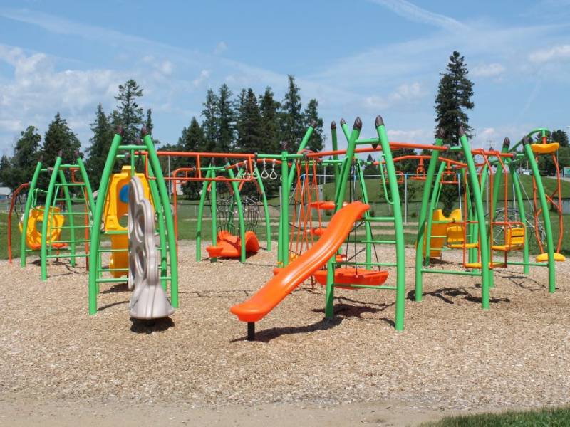 Modern outdoor playground in Shannon Quebec with green and orange climbing frames, slides, and swings made from durable materials.